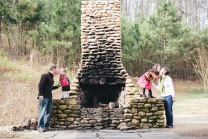 Two parents smooching their little girls on sides of Rope Mill outdoor fireplace