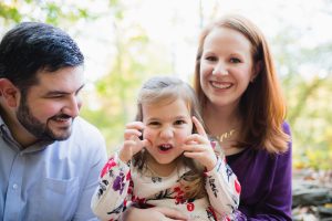 Goofy little girl making faces while her parents laugh