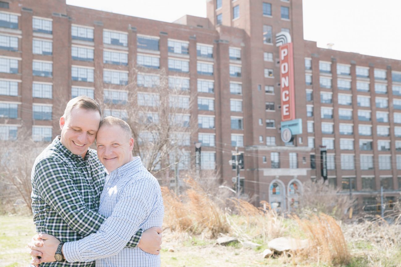 Two men hugging and smiling in front of Ponce City Market building.