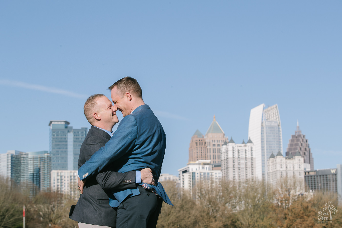 Two men hugging and bumping noses with Atlanta skyline in background