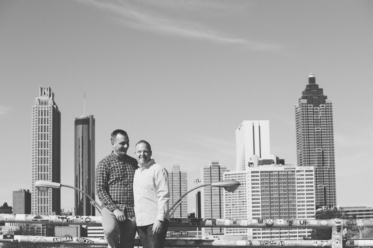 Two men standing on Jackson Street Bridge with Atlanta skyline in background.