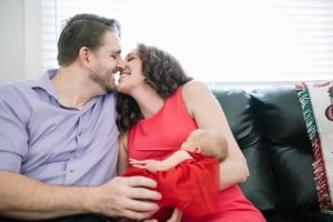 New parents about to kiss while holding newborn daughter