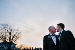 Two grooms almost kissing at sunset