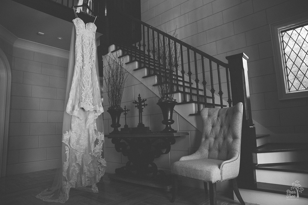 Gorgeous lace wedding gown hanging in luxurious two story foyer.