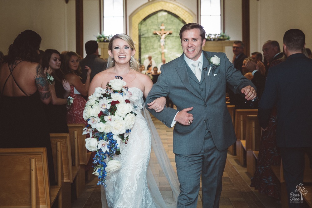 Elated bride + groom walk out of St. Ann's Church after marriage ceremony.