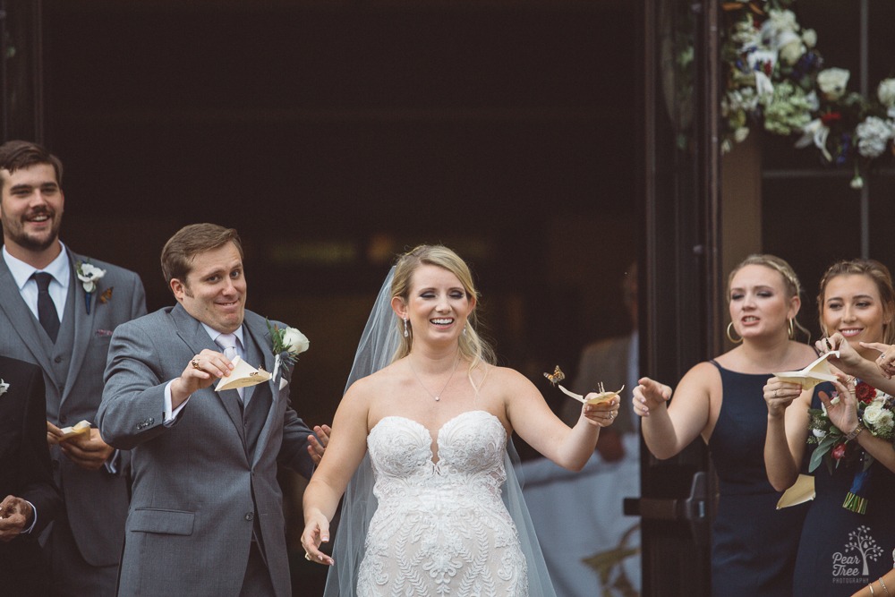 Bride + groom release butterflies after ceremony and make faces as some take off and others aren't quite ready to fly.