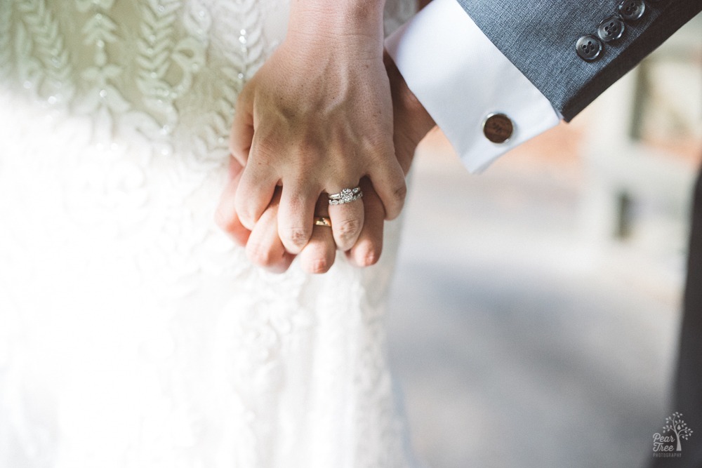 Bride's hand intertwined in her groom's hand.