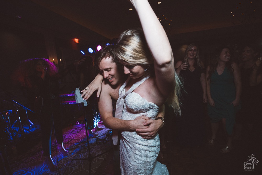 Shirtless groom holding his new wife wearing her wedding gown and his tie.