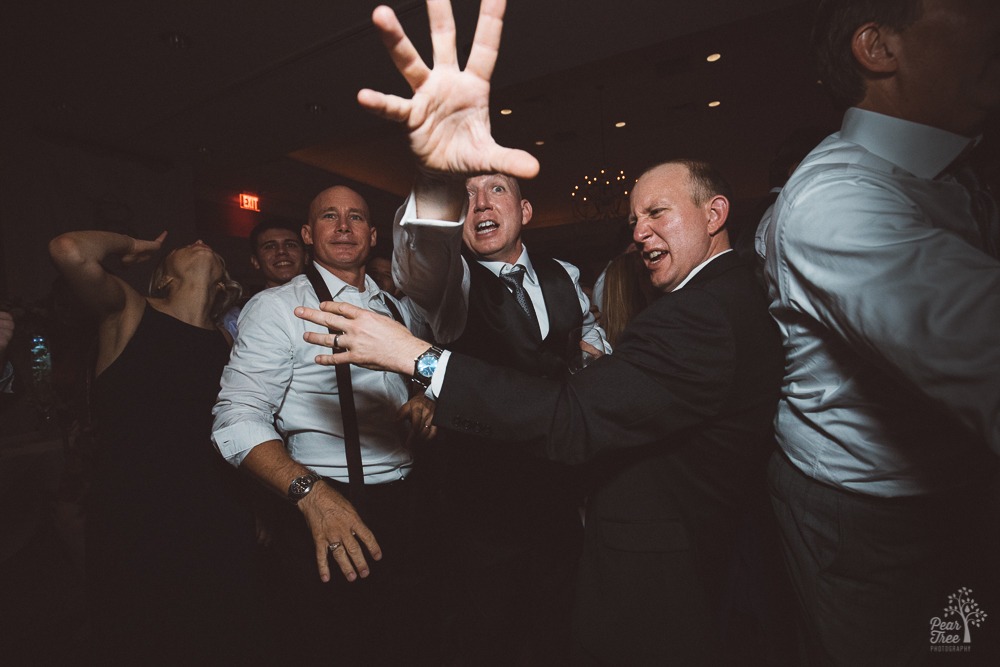 Bride's dad joking with brothers and reaching for camera to block all evidence of shenanigans.