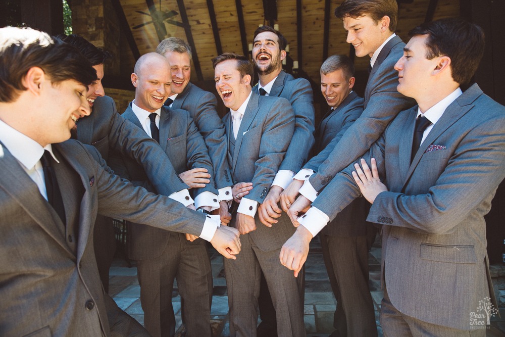 Groom laughing with groomsmen as they show off their cuff links.