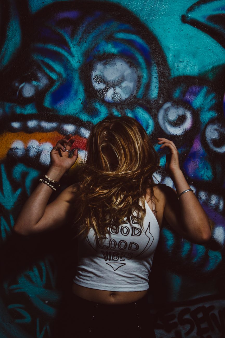 High school senior girl dancing and shaking her hair in front of grafitti