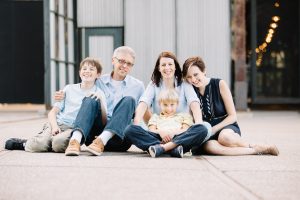 Smiling parents with three happy kids sitting on Minneapolis patio