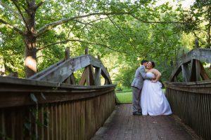 Bride + Groom embracing on Mountain Park bridge in Roswell for Atlanta wedding photographer