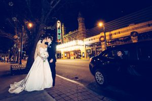 Bride + Groom kissing with Atlanta Fox Theater in background and as car stops to watch