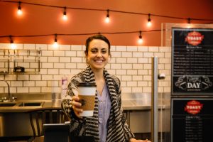 Commercial business owner holding out a cup of coffee