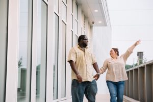 Engaged couple walking + being silly around Buckhead buildings