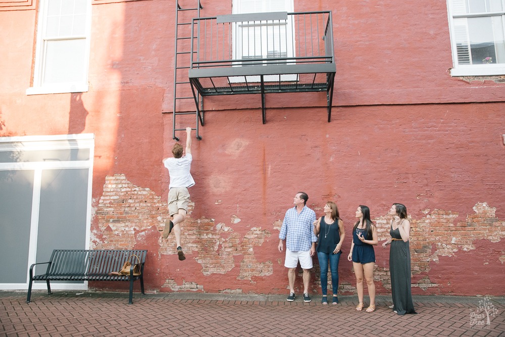 Family looking at the oldest jumping up a wall to grab a fire escape in downtown Canton