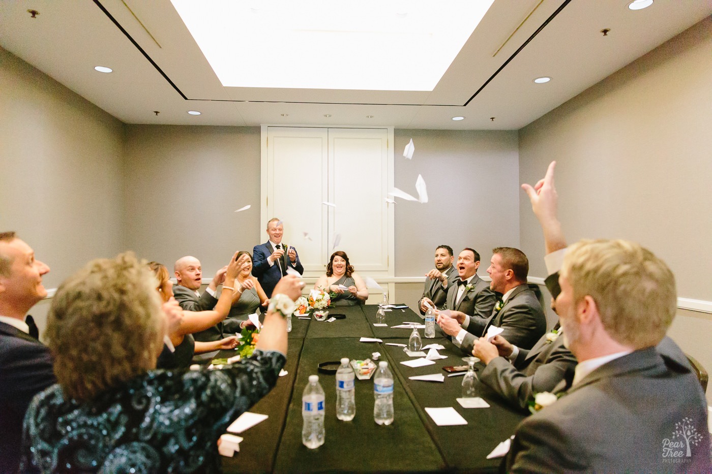 Wedding party throwing paper airplanes inside Renaissance Concourse Atlanta hotel conference room before wedding ceremony.