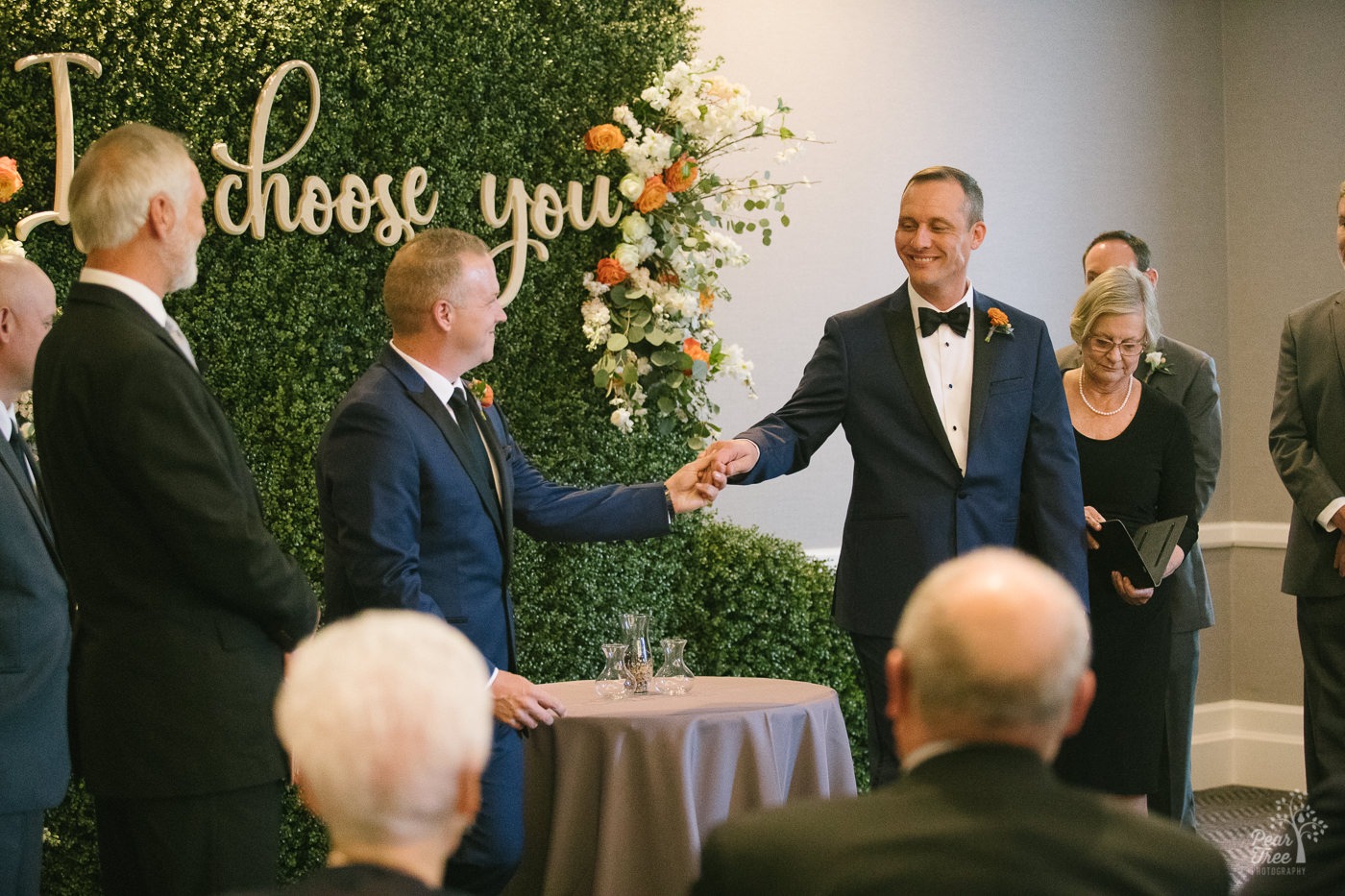 Two grooms holding hands after sand ceremony in their wedding.