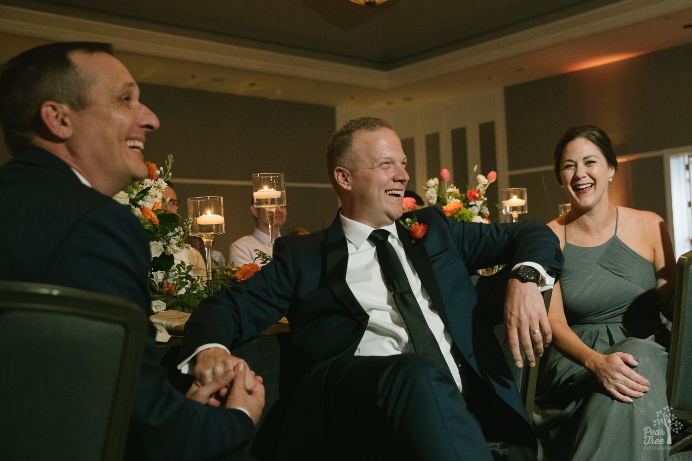 Two grooms and one maid of honor laughing during toasts at reception inside Renaissance Concourse Atlanta Airport Hotel.