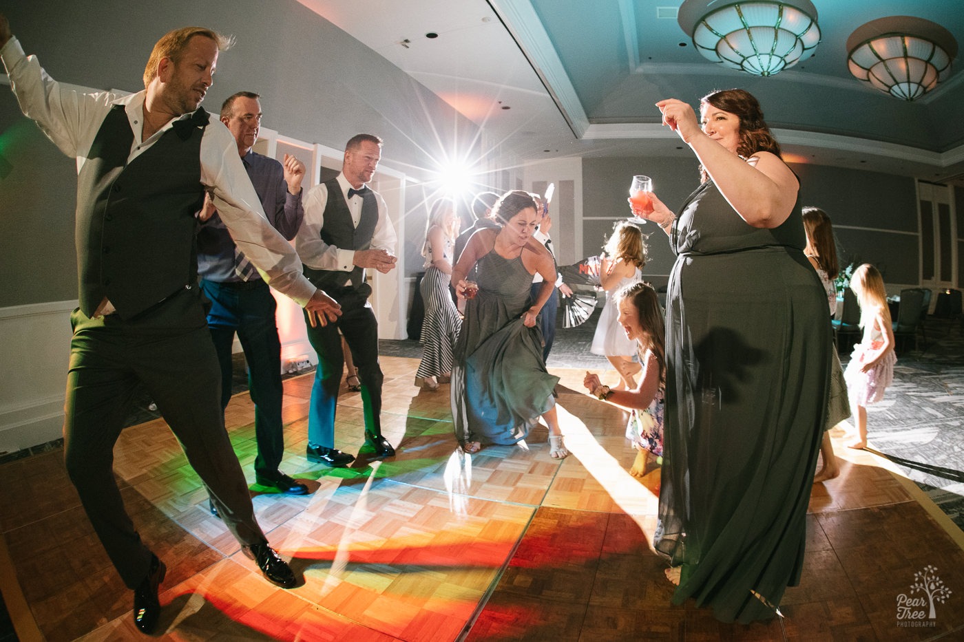 Groomsmen dancing with Matron of Honor, Maid of Honor, and children on dance floor.