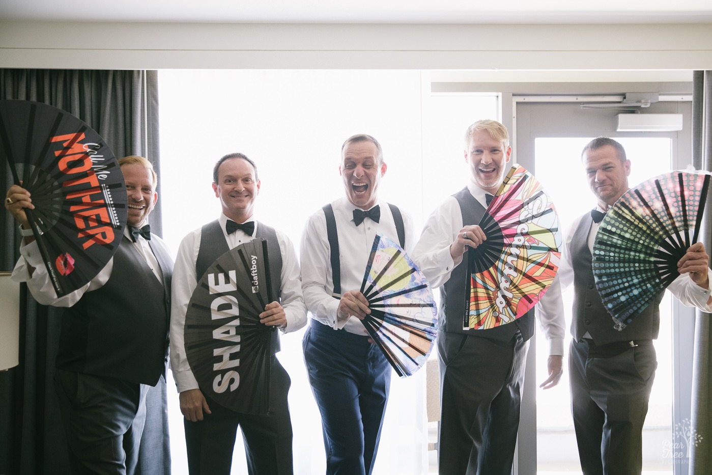 Groom with four groomsmen showing off their large, fancy fans.