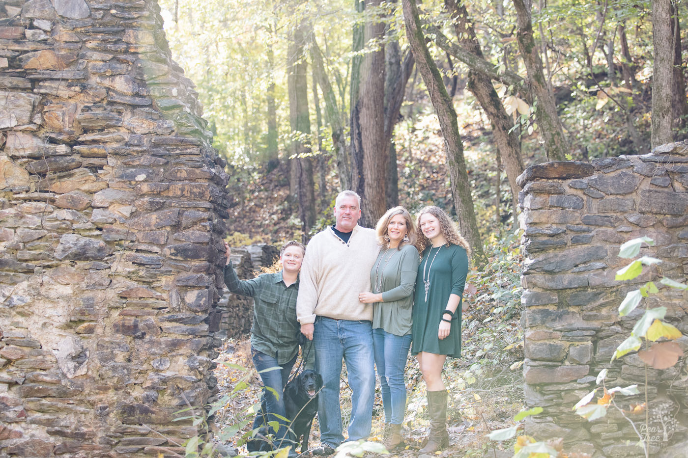 Parents with teenage daughter, son, and family black lab standing in paper mill ruins in East Cobb.
