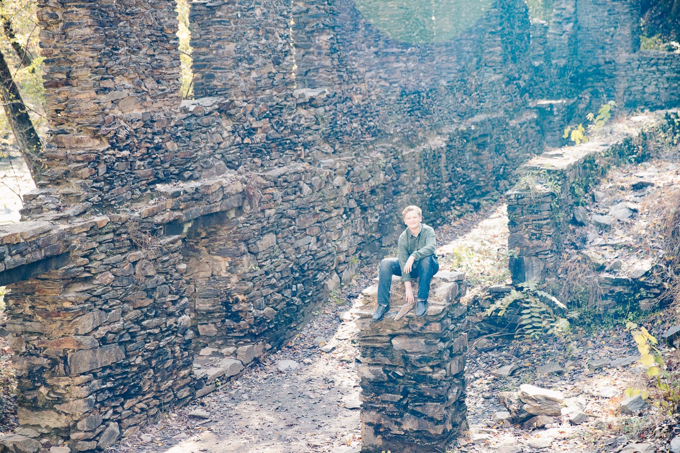 Teenage boy sitting on pillar inside old paper mill ruins at Sope Creek.