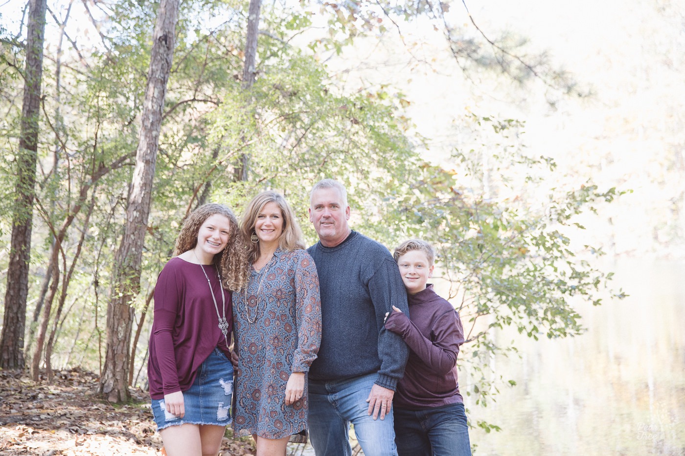 Happy family of four standing together in woods near Sope Creek.