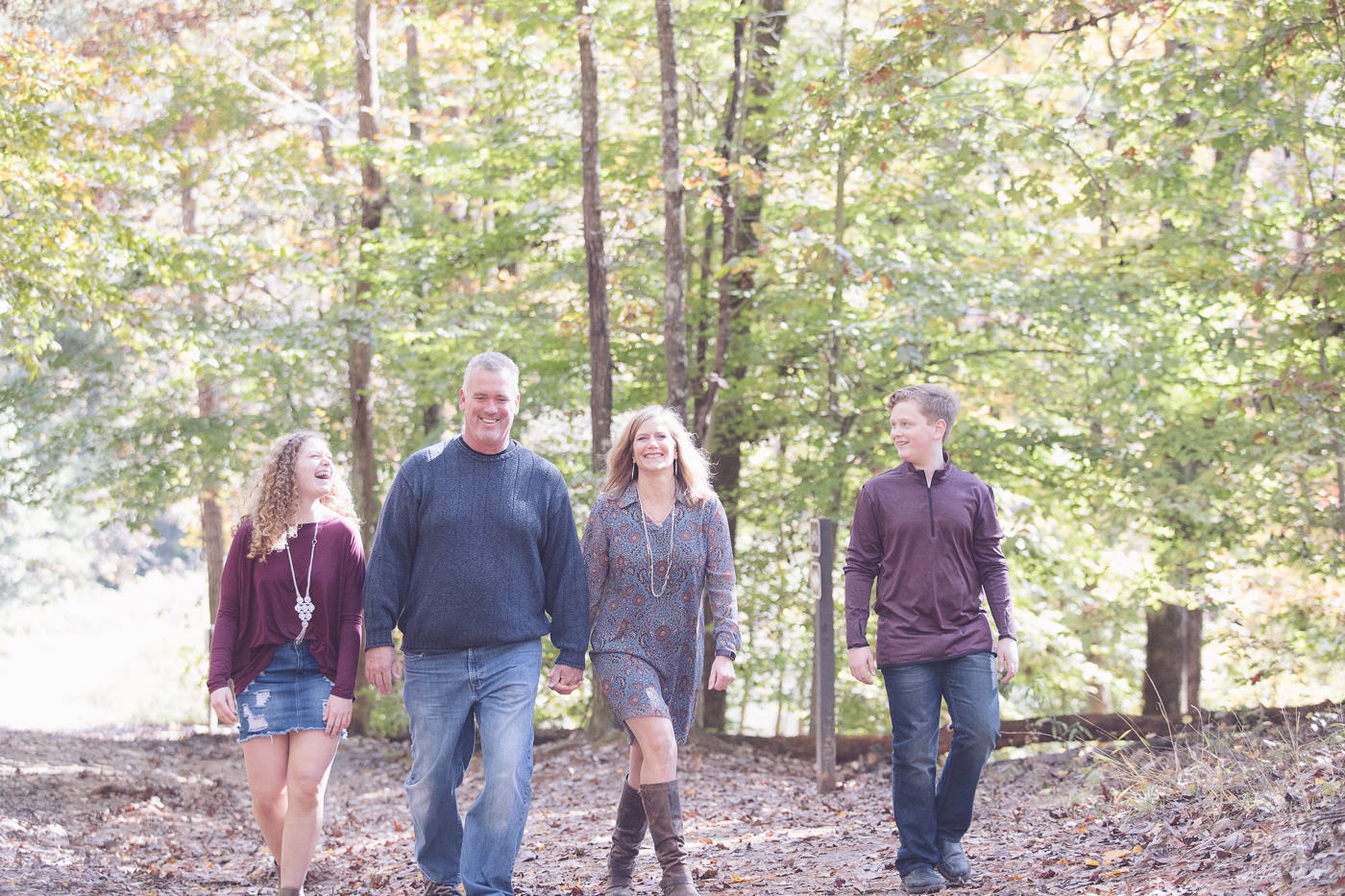 Family of four laughing while walking through woods in East Cobb.