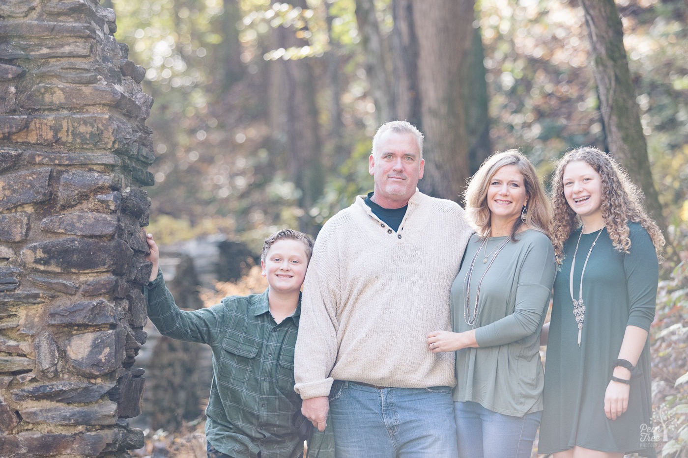 Family of four standing close smiling and laughing.