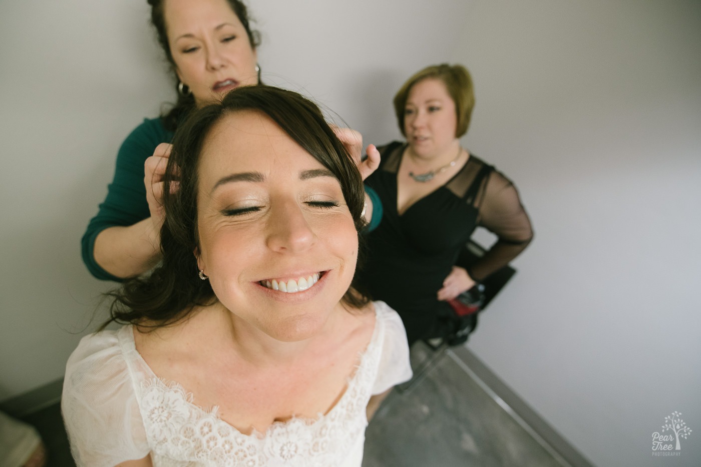 Bride smiling while her best friend is adjusting her hair.