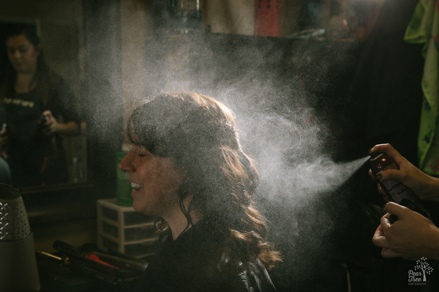 Hair spray misting through the air onto bride's finished curls.