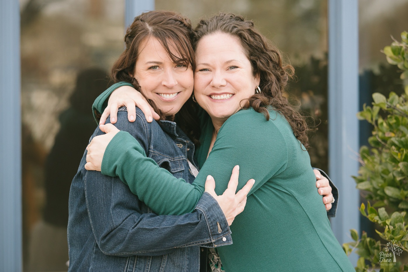 Two brunette best friends hugging each other and smiling.