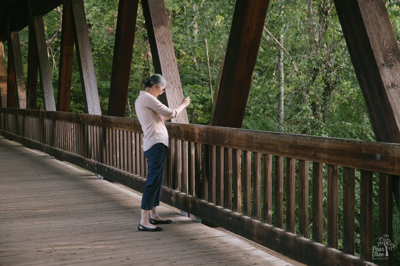 Chinese woman using her cell phone to take pictures of Vickery Creek from the covered bridge.