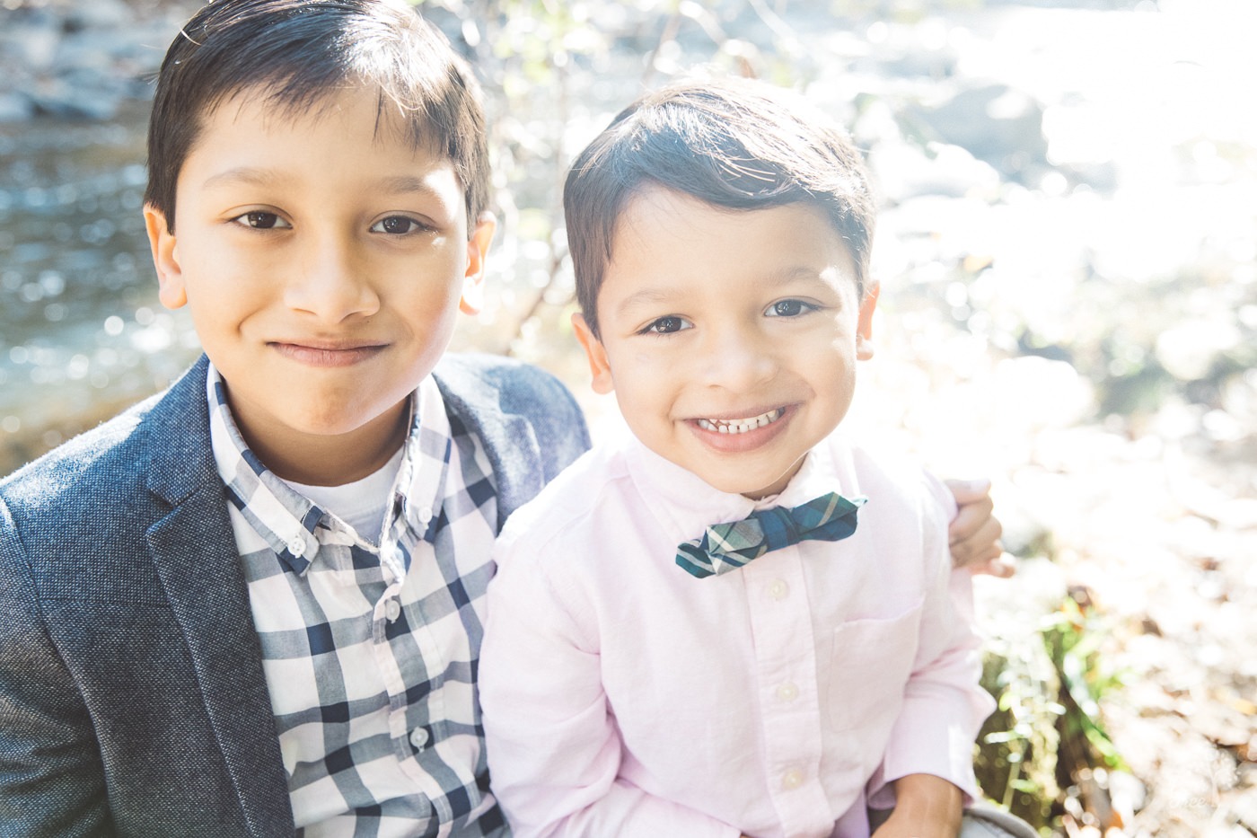Two brothers dressed fancy and smiling sweetly while sitting next to each other at Sope Creek.