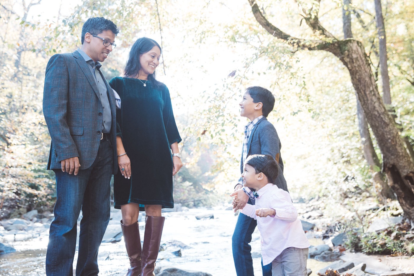 Family of four standing on shoals at Sope Creek and smiling at each other.