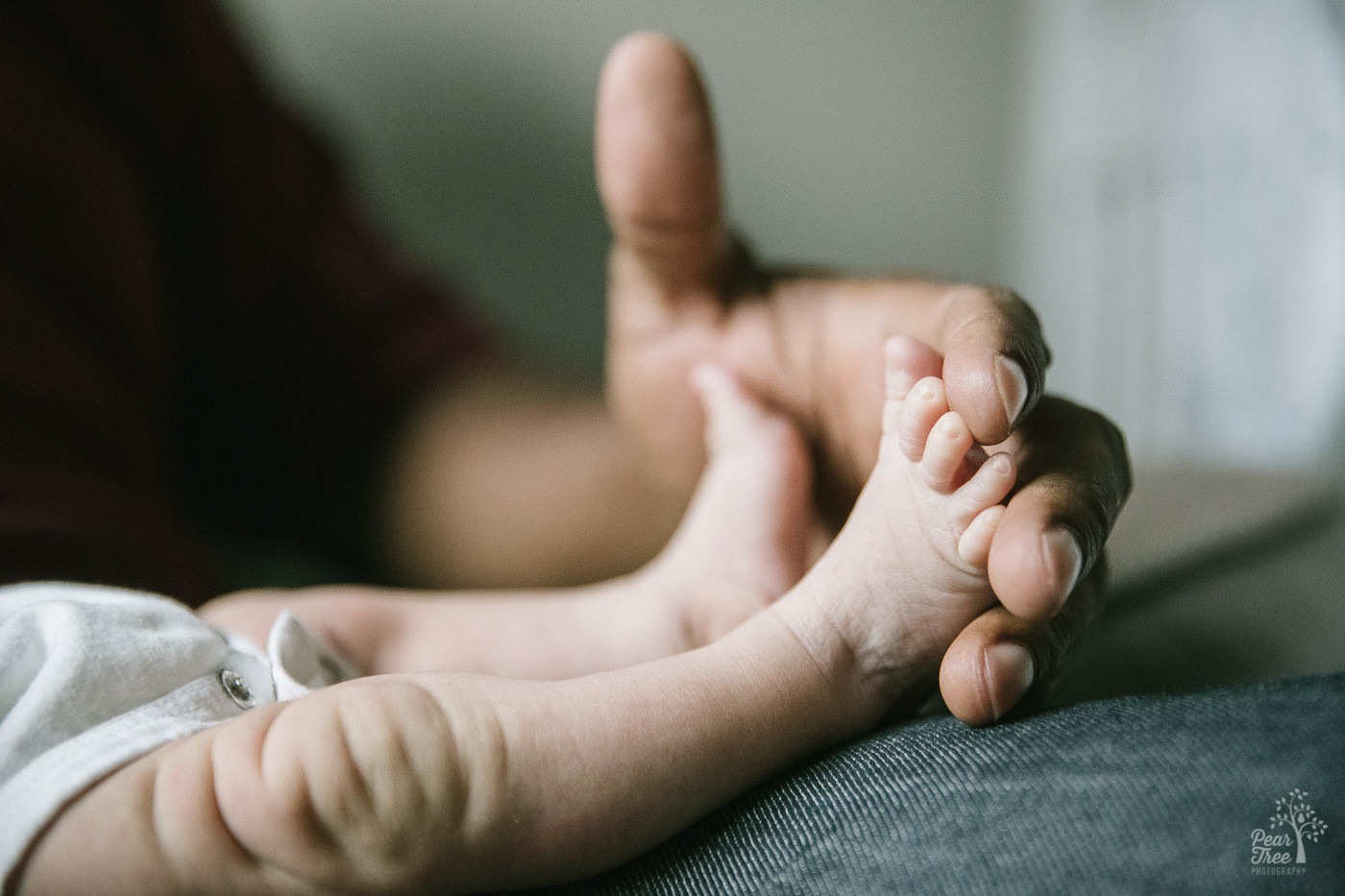 Tiny newborn legs and feet stretched out into Dad's hand.