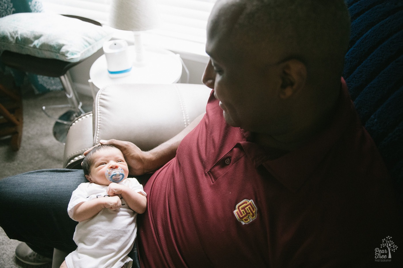 Dad holding five day old son in his lap during their legacy lifestyle newborn session