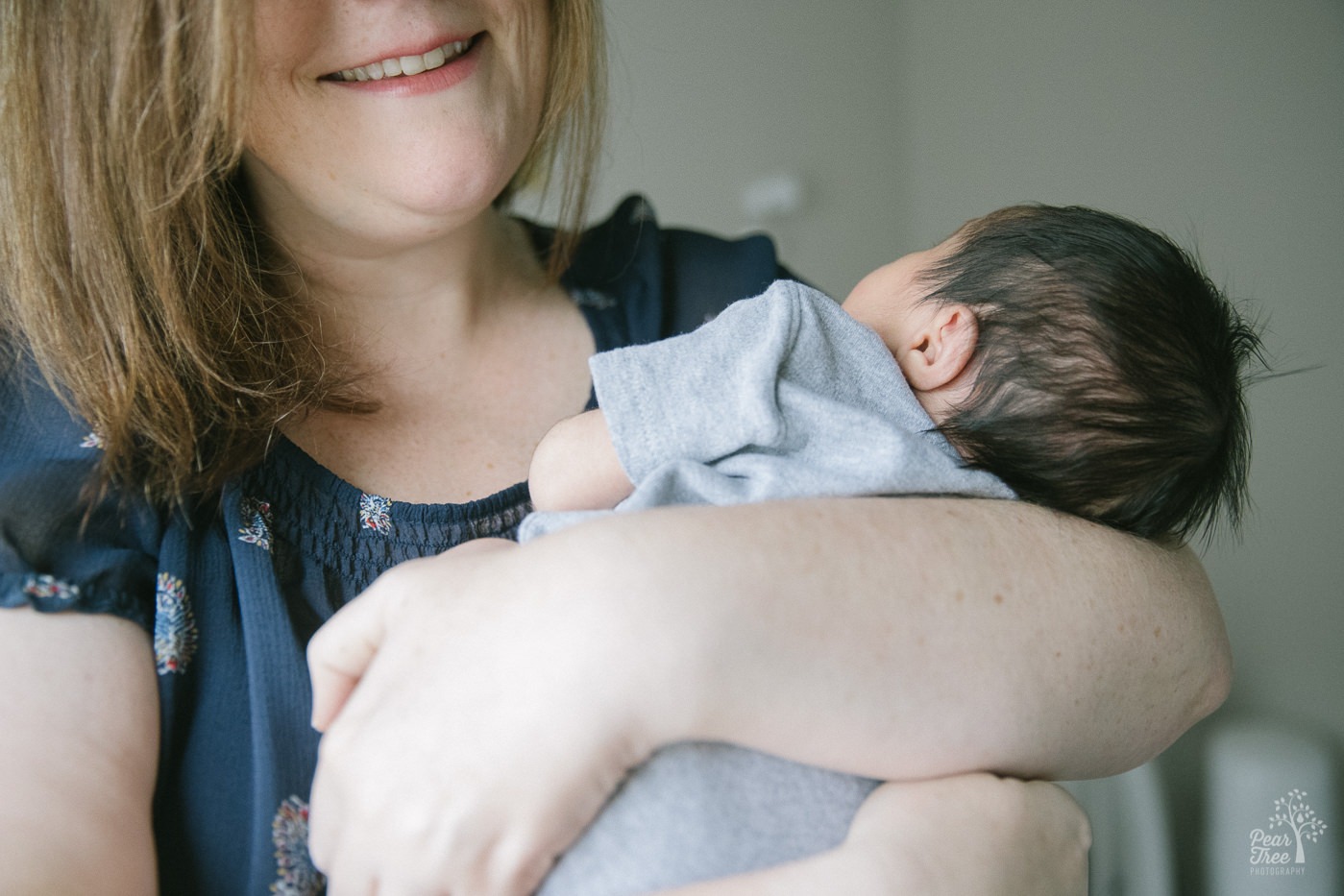 Smiling mom holding her newborn son close to her chest.