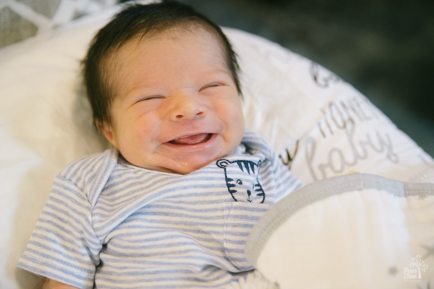 Smiling five day old in zebra onesie.