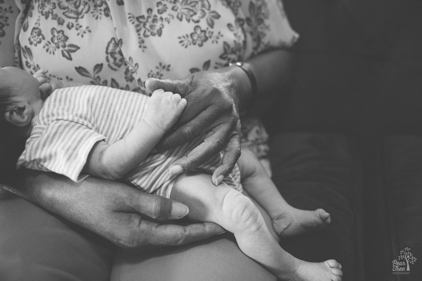 Grandma's hands holding her newborn grandson in her lap.