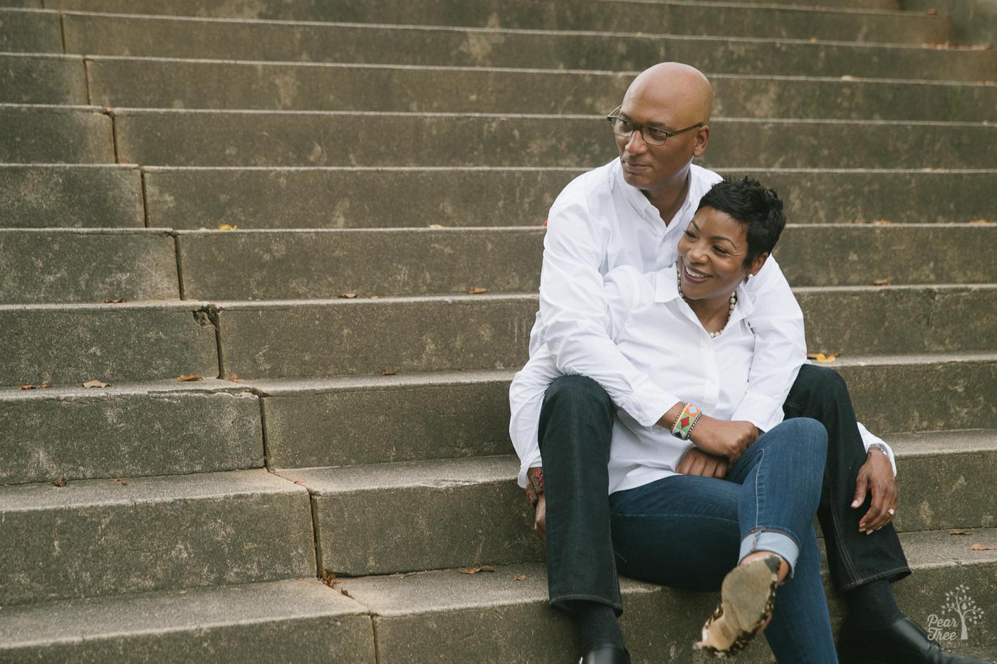 Happy engaged African American couple sitting on Piedmont Park steps holding each other.