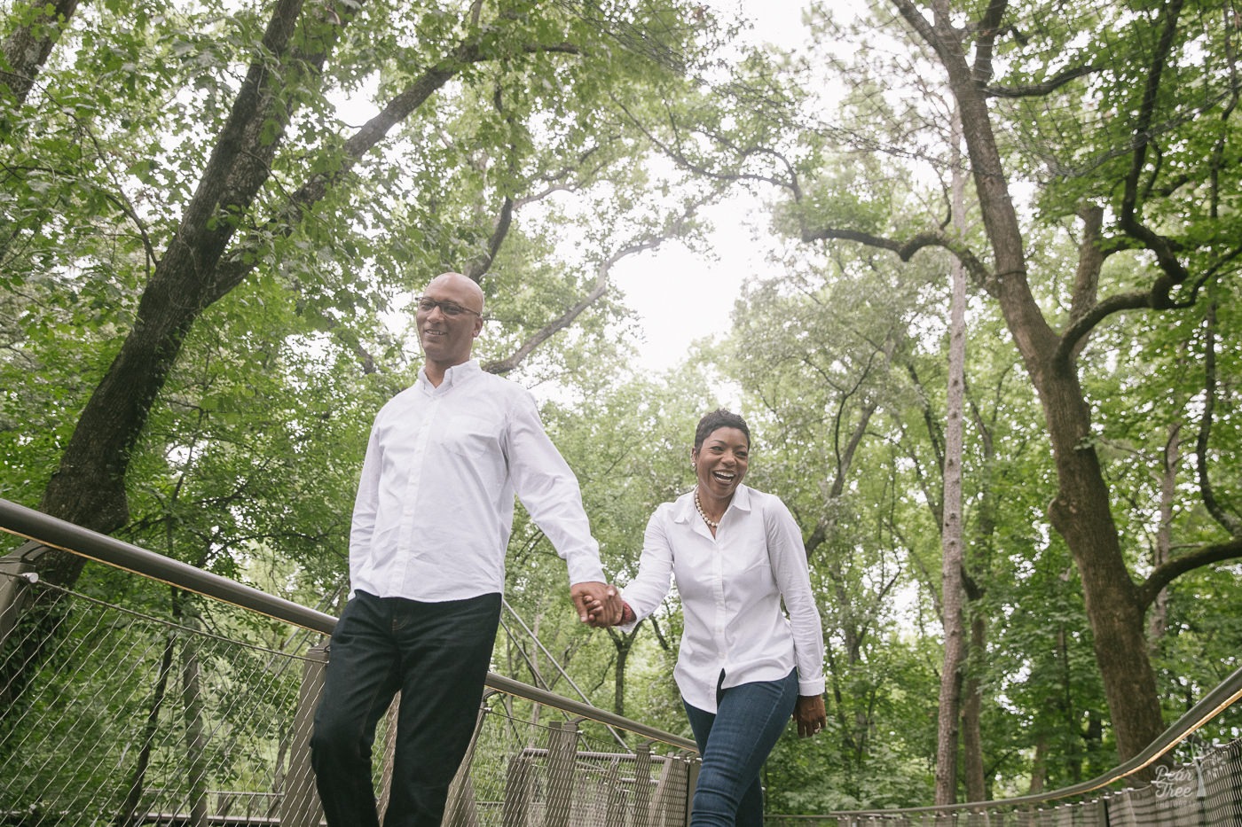 Laughing couple holding hands while walking over the Atlanta Botanical Gardens canopy walkway