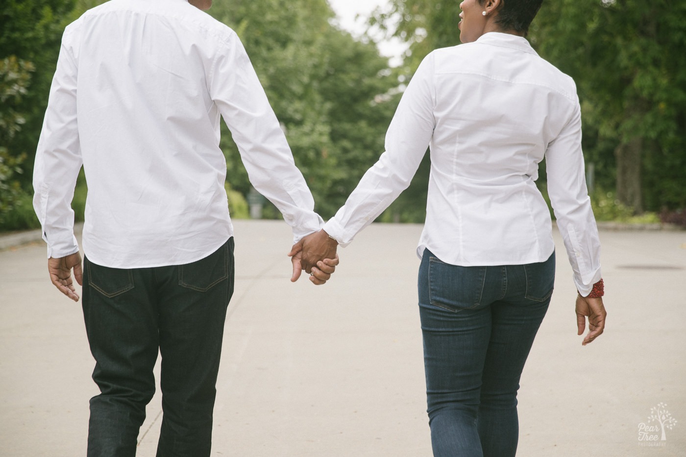 Couple holding hands during their engagement session while walking into Piedmont Park from Atlanta Botanical Gardens