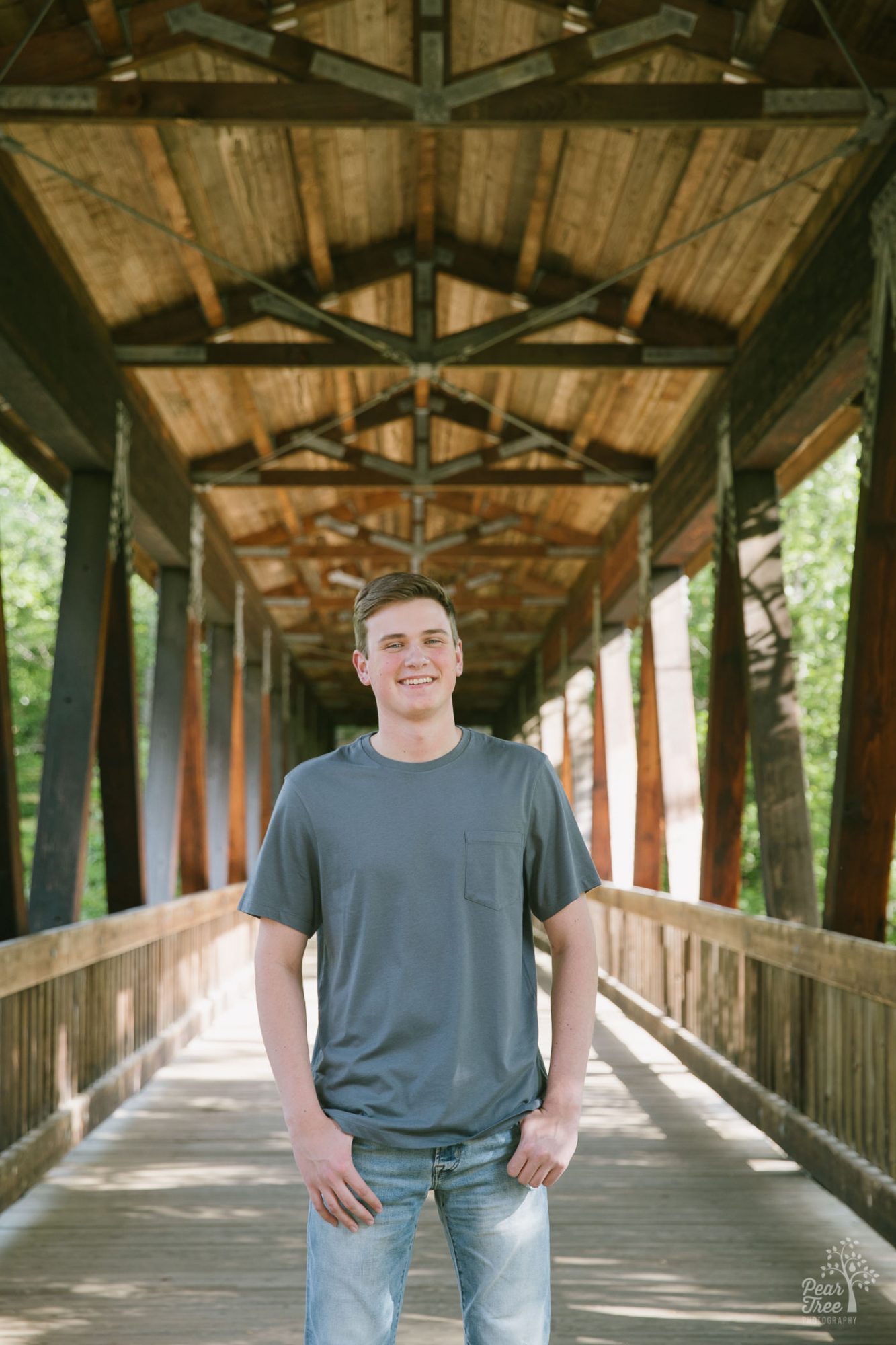 Woodstock High school senior boy standing in covered bridge at Roswell Mill.