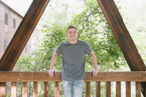 Woodstock High School senior smiling while leaning against Roswell Mill bridge railing