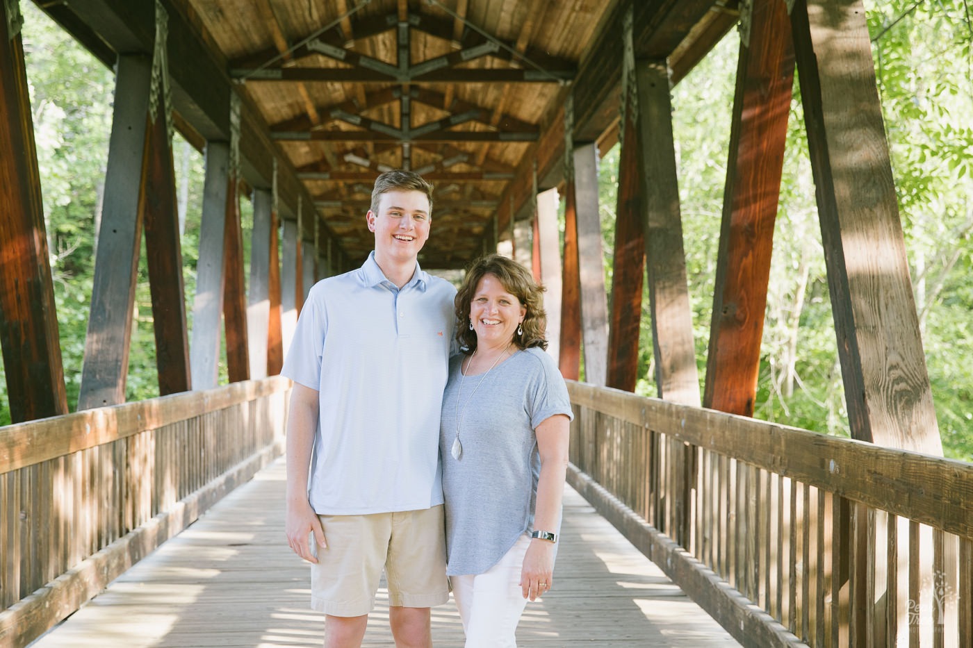 Mother + son standing together inside the covered bridge at Roswell Mill.
