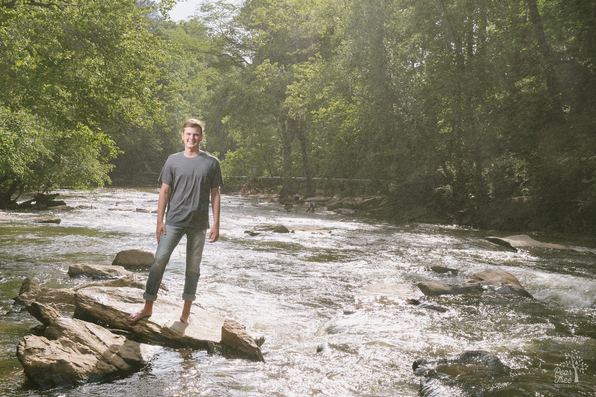 High school senior boy standing on shoals at Vickery Creek near Roswell Mill