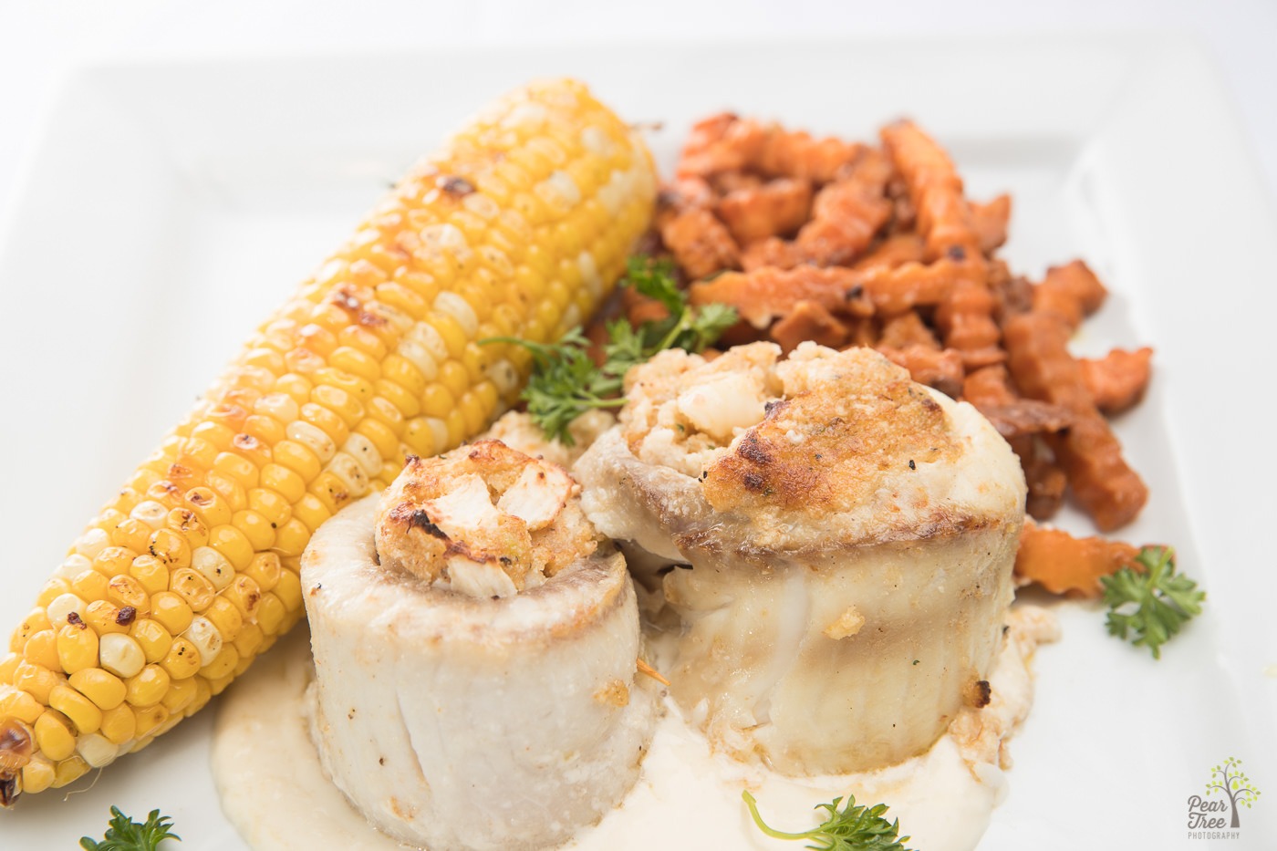 Stuffed tilapia rolls with cajun corn on the cob and crinkly sweet potato fries made by Divine Taste of Heaven.